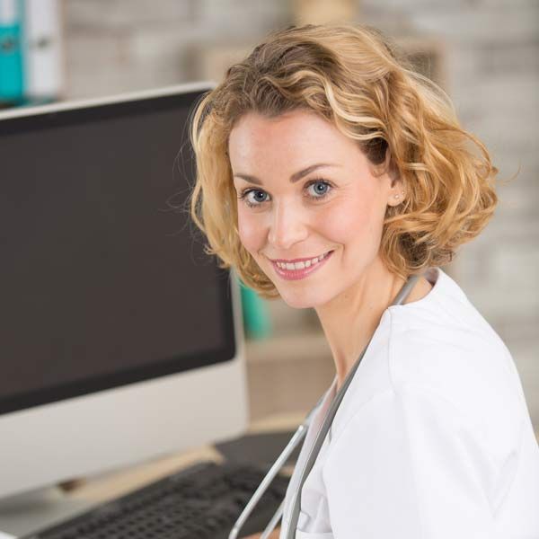 A female doctor is sitting in front of a computer and saying Say Goodbye to Wrinkles and Sagging Skin! Contact Us for a Skin Microneedling Consultation
