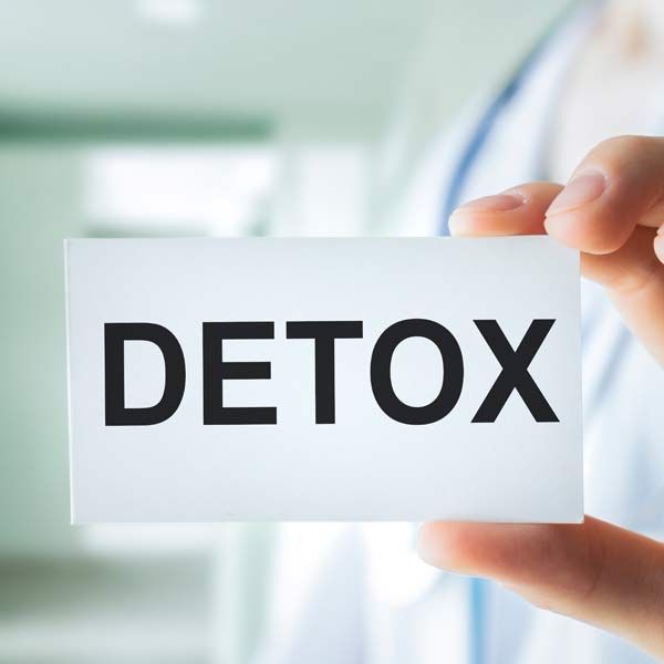 A person is holding a card that says detox representing Detoxification Programs