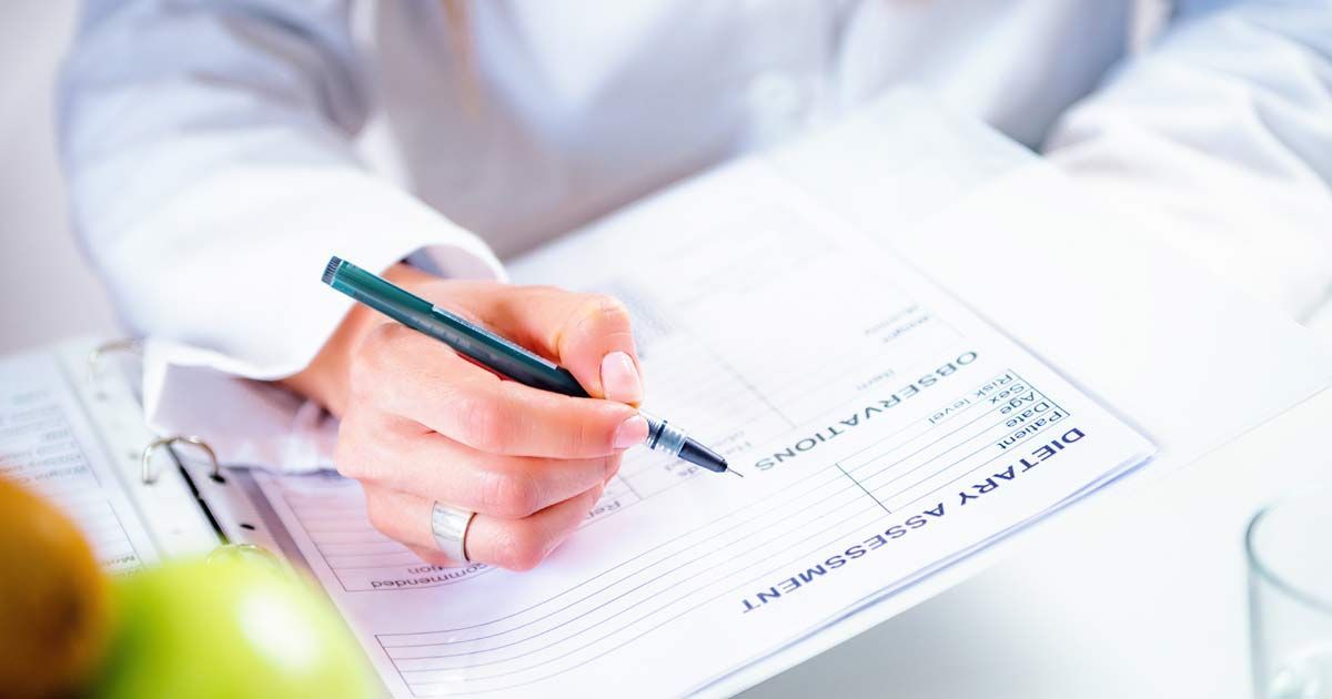 A doctor is writing a dietary assessment on a piece of paper with a pen for Medical Diet Plans NJ and NYC at Victory Medical Institute