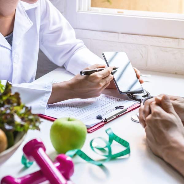 A doctor is talking to a patient while holding a cell phone talking about Diet Plans with a Victory Medical Dietitian and Nutritionist.
