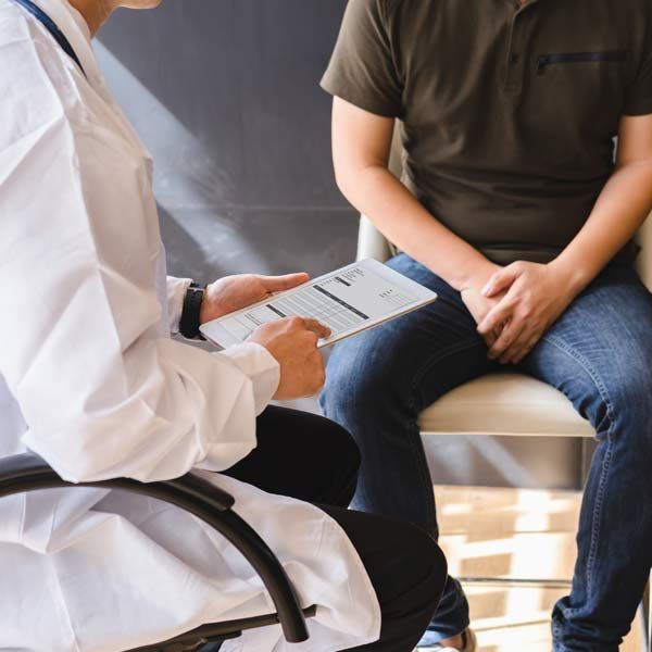 A doctor is talking to a patient who is sitting in a chair, considering Sexual Dysfunction Treatments NJ and NYC - Victory Medical Institute