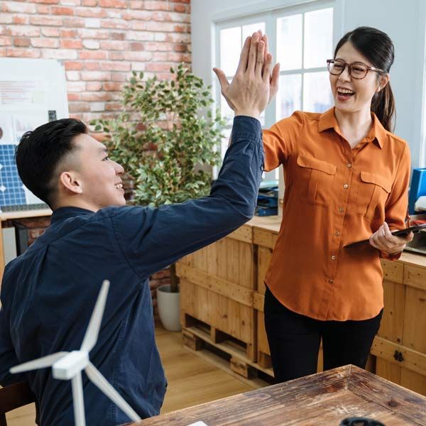 A man and a woman are giving each other a high-five in an office, representing get up and go energy IV therapy