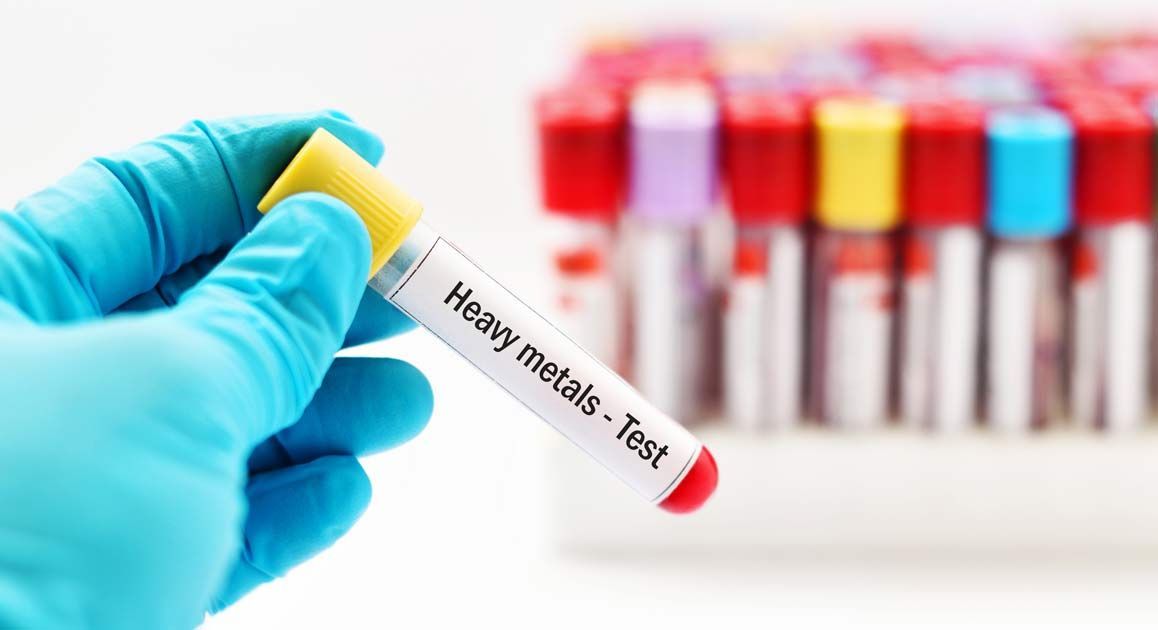 A gloved hand holding a test tube labeled  Heavy Metal Detox NJ - Dr. Kamal Kalsi