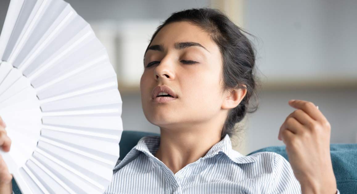 A woman having hot flashes, waiting for Hormone Imbalance Treatments at Victory Medical Institute waiting room