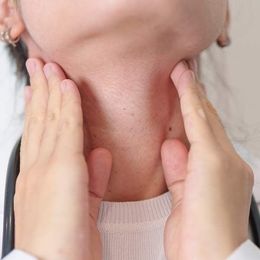 A woman is holding her neck with her hands while wearing a stethoscope. during medical treatments