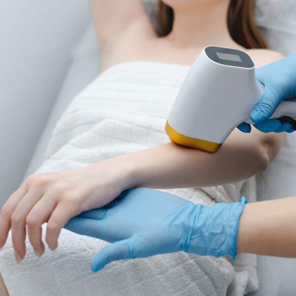 A woman is getting a laser hair removal treatment on her arm.