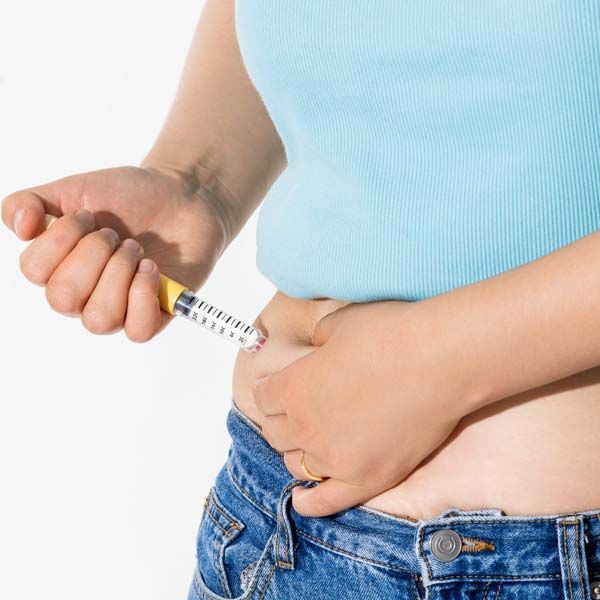A woman is injecting herself with GLP-1 Therapy to lose weight