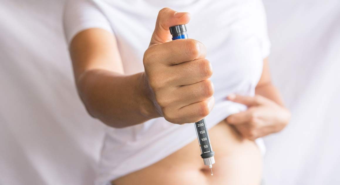 A woman is holding a pen over her stomach for GLP-1 Therapy NJ and NYC - Victory Medical Institute
