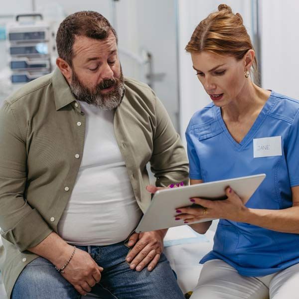 A man and a nurse are looking at a tablet together, showing the patient who Who Can Benefit from GLP-1 Therapy in NJ and NYC