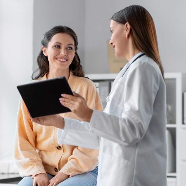 A doctor is talking to a patient while holding a tablet, explaining Victory Medical Expertise and Training for Peptide Injection Therapy