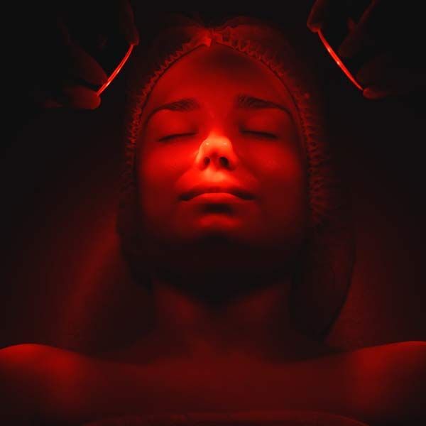 A woman is getting a red light treatment on her face. Phototherapy and Red Light Therapy
