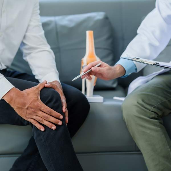 A man is sitting on a couch talking to a doctor about his knee pain and Musculoskeletal Disorders