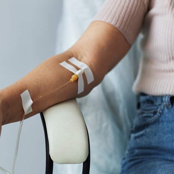 A woman is sitting in a chair with an iv in her arm. What Is IV Therapy?