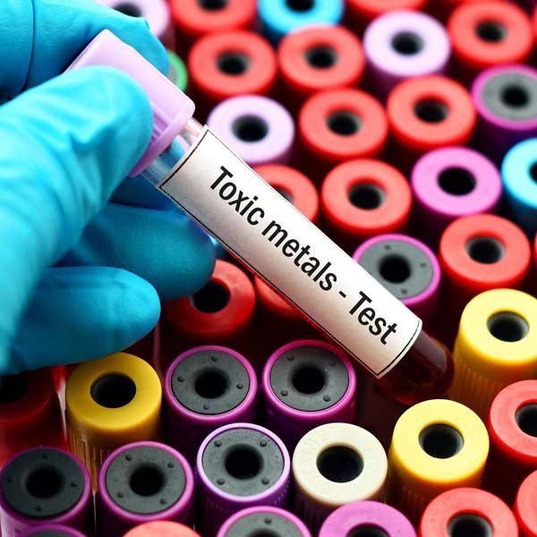 A hand is holding a test tube that says toxic metals test. Heavy Metal Detox