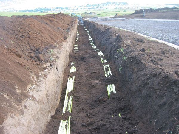 a trench filled with dirt and a road in the background