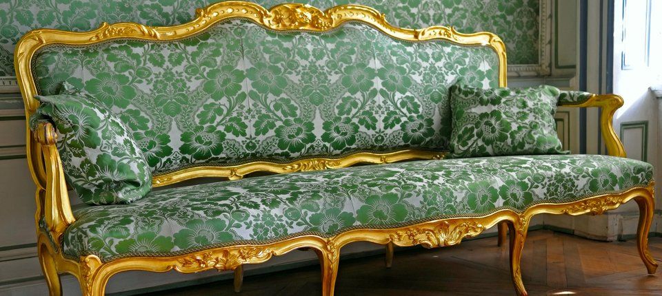 A grand sofa with golden frame and stylish green upholstery