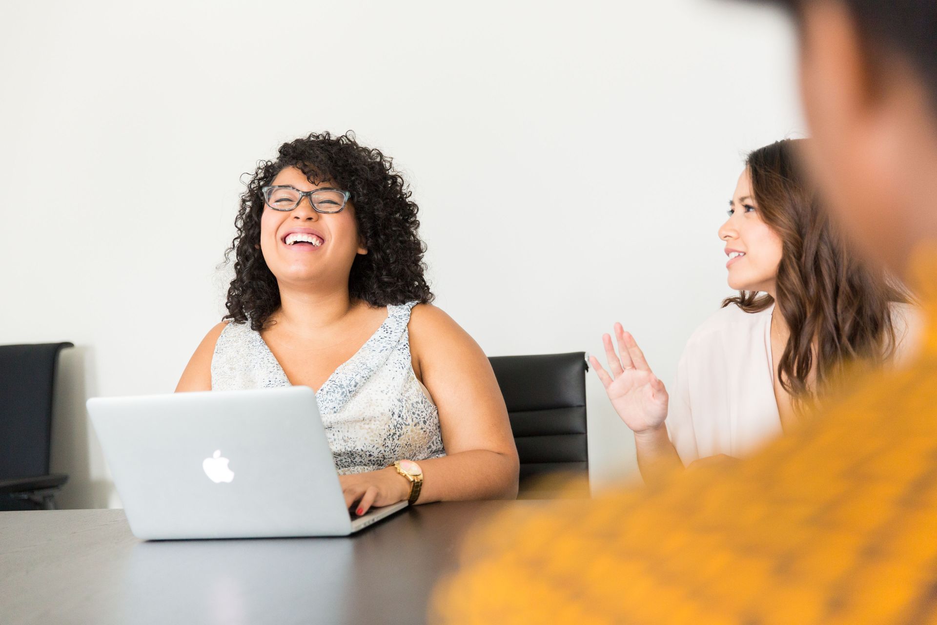 People in a meeting, smiling and talking around a laptop in a bright office