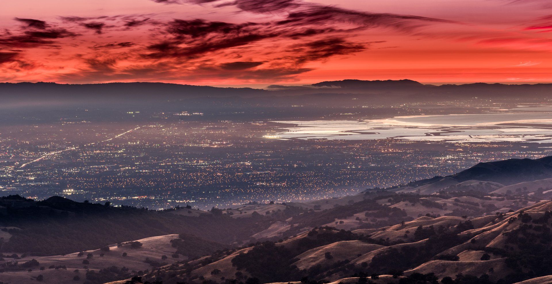 A sunset over a city with mountains in the background