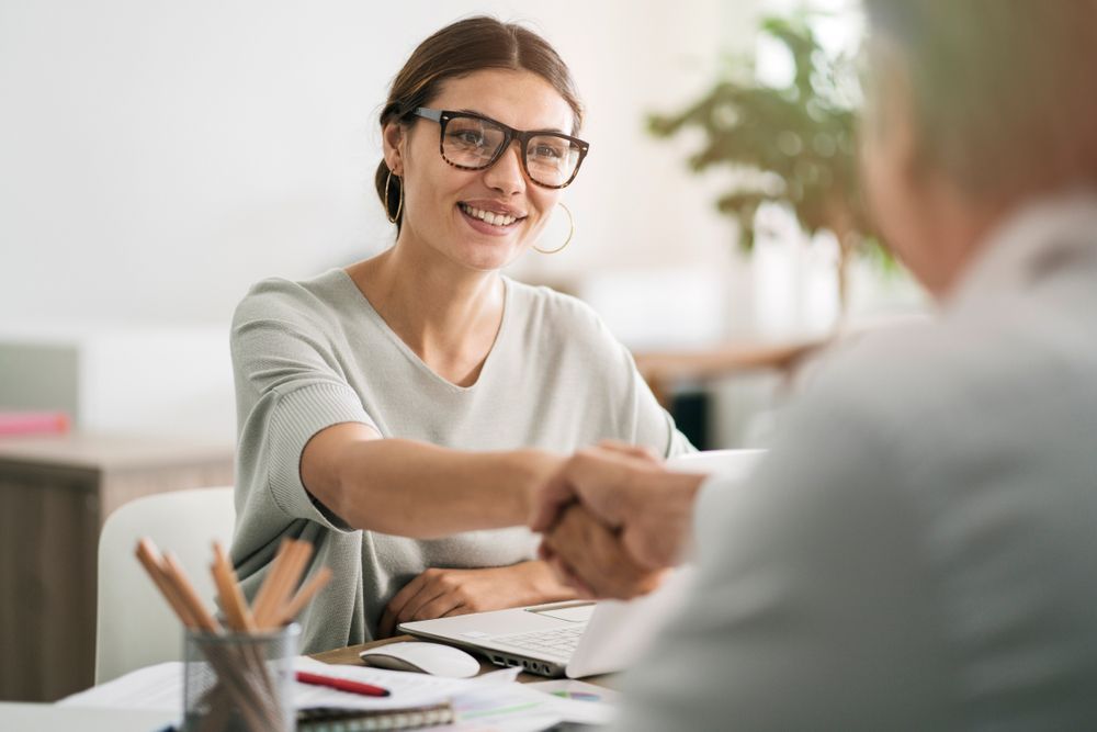 A woman is shaking hands with a man at a table.