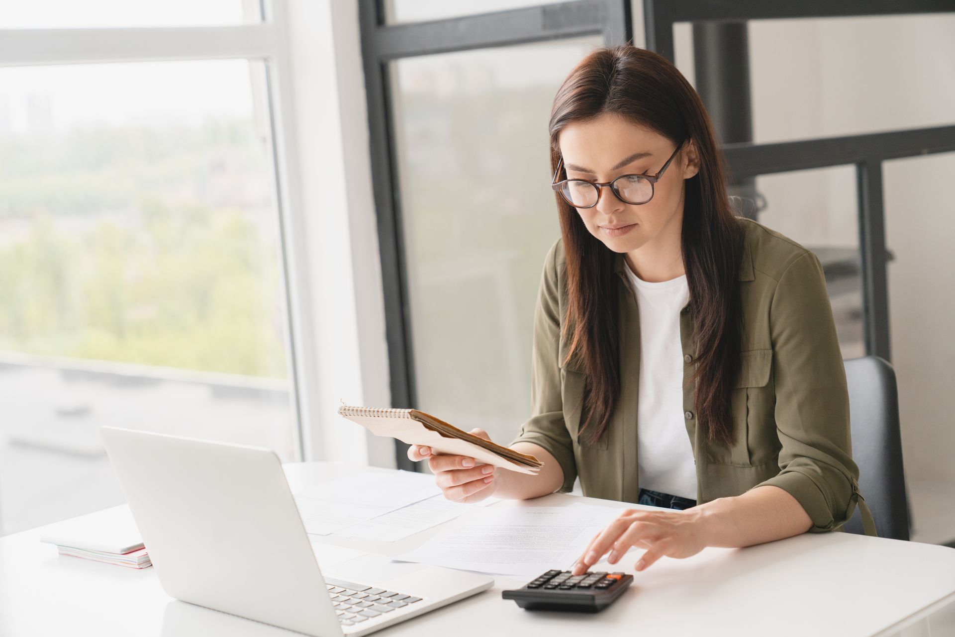 A young woman sits at a desk wondering if she should look for a new San Diego Employee Benefits Broker