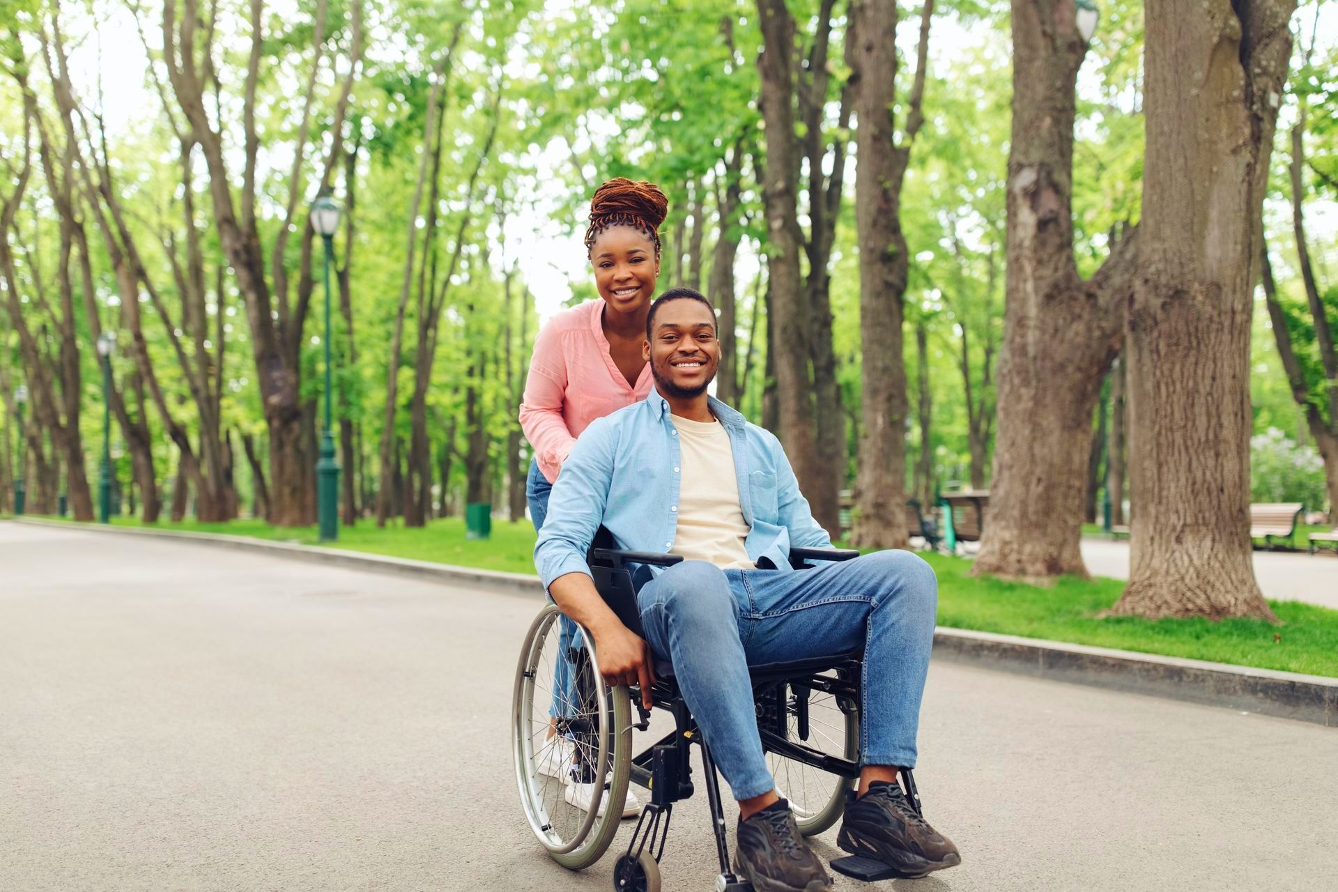 a woman is pushing a man in a wheelchair in a park 
