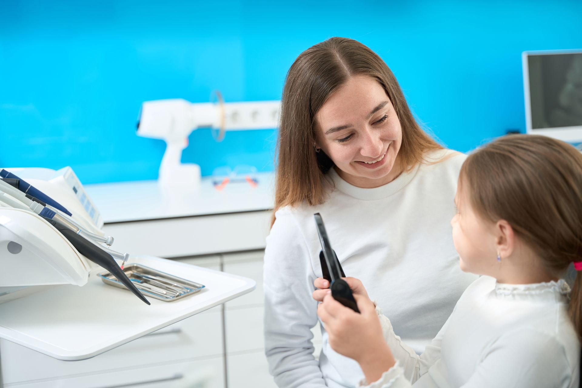 the dentist hands the child a mirror so she can admire her fresh, clean smile