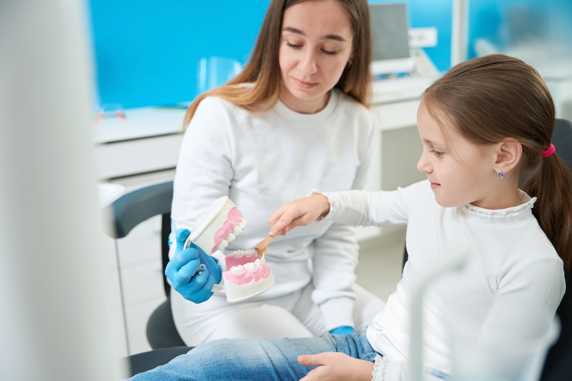the child practices brushing on fake teeth, while the dentist discusses hmo vs ppo vs epo