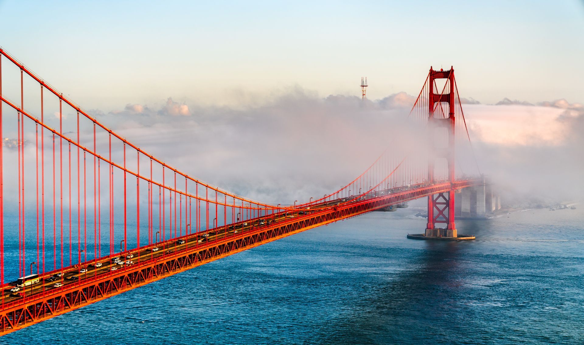 The golden gate bridge is covered in fog on a foggy day.
