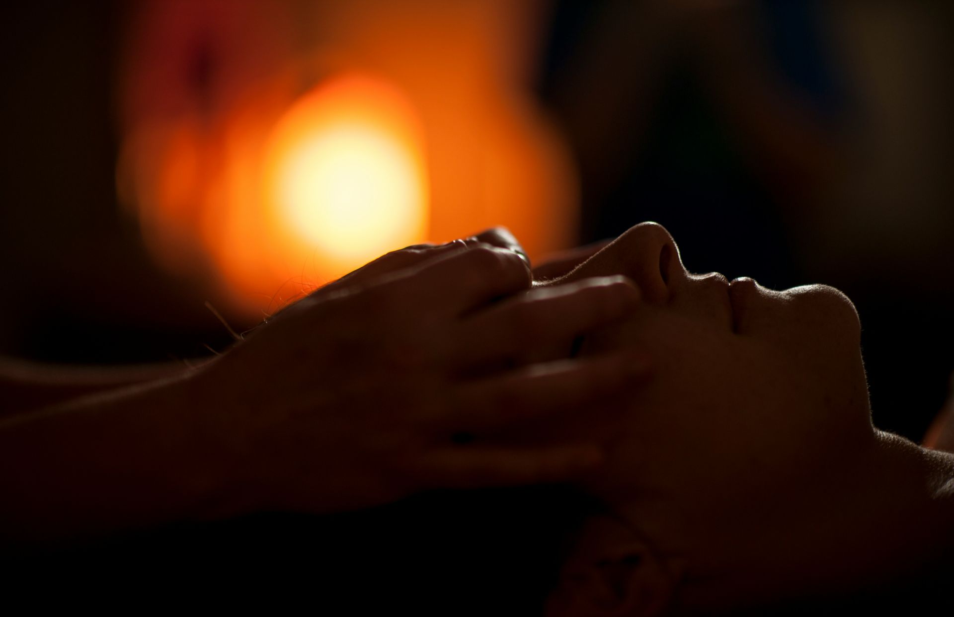 A woman receiving a head massage in a dim spa.