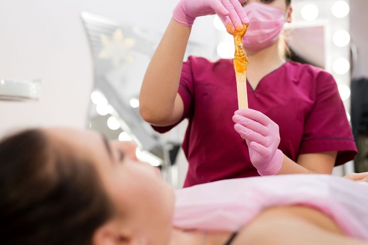 A woman is getting a sugaring treatment at a beauty salon.