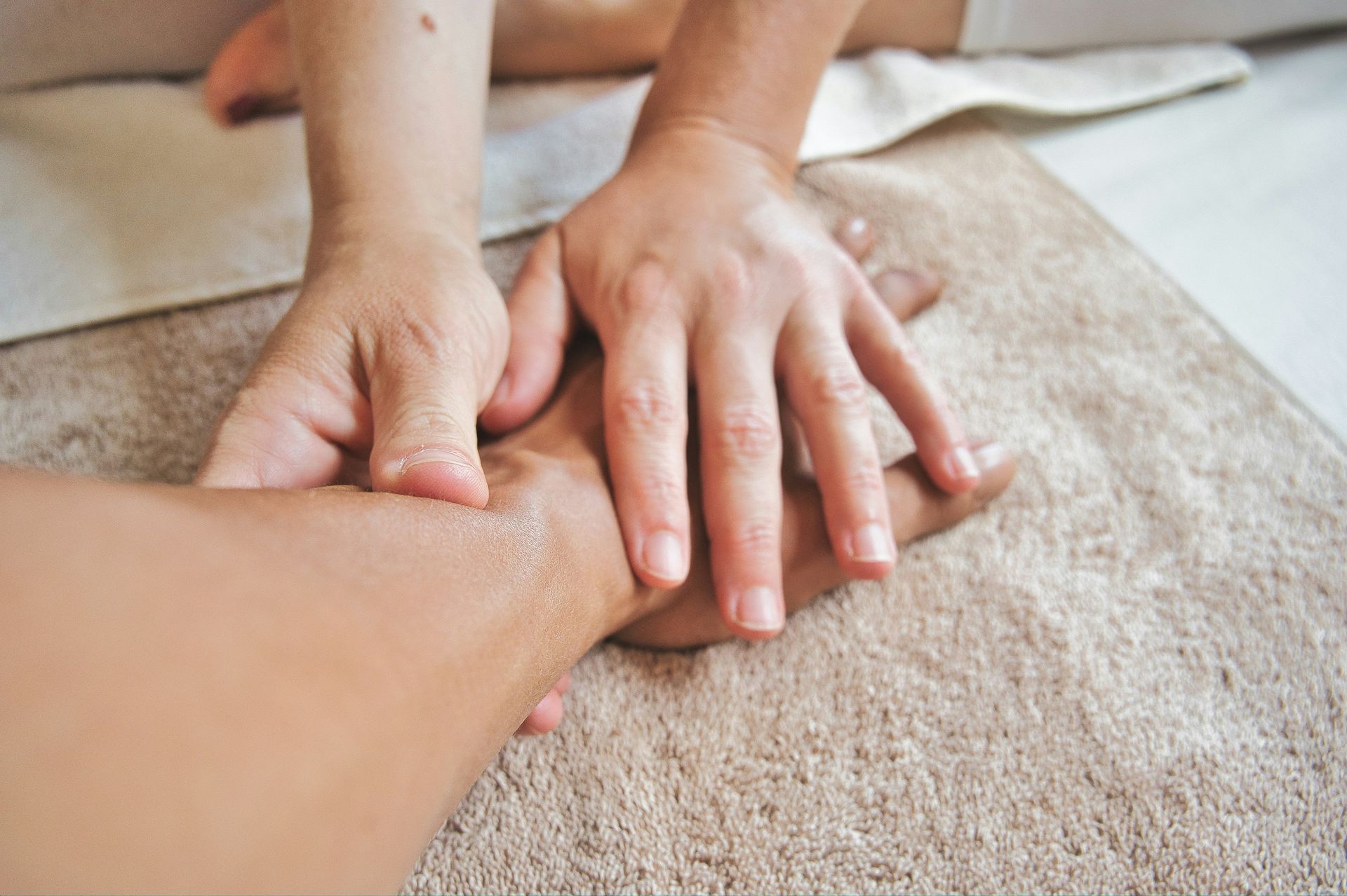 A masseuse applying pressure on a person's forearm.