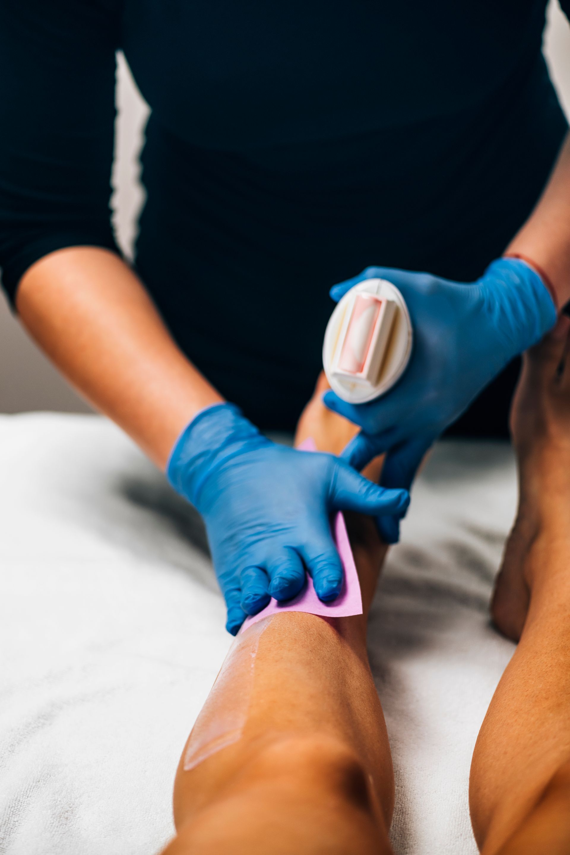 A woman is waxing another woman 's leg in a beauty salon.