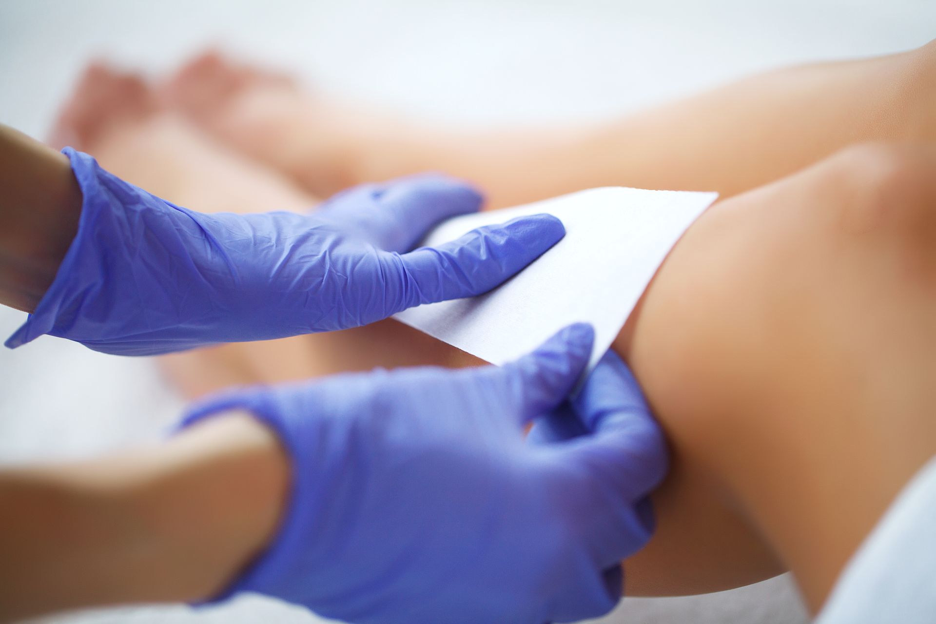 Beautician applying wax strips to a client's leg - Shirley's Mind & Body