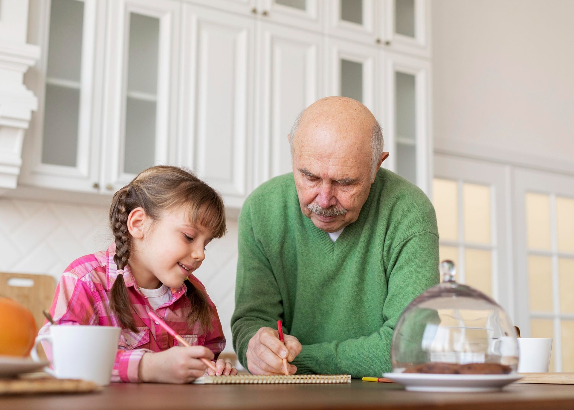 Smiling older couple looking at a phone together, beside an open laptop and a coffee cup.