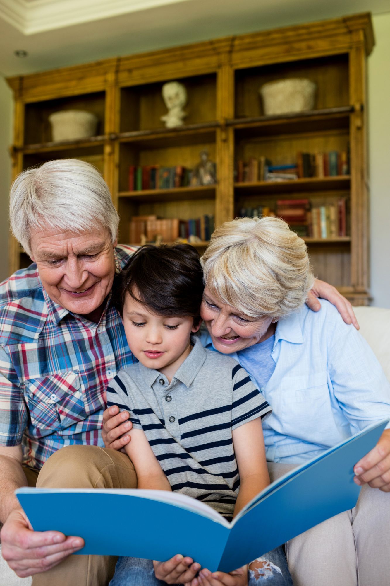 Senior couple using a phone and laptop at a table. Smiling, light-filled room.