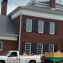 A white truck is parked in front of a large brick building.