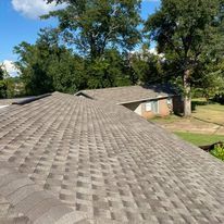 A roof of a house with a lot of shingles and trees in the background.