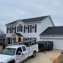 A white truck is parked in front of a large white house.