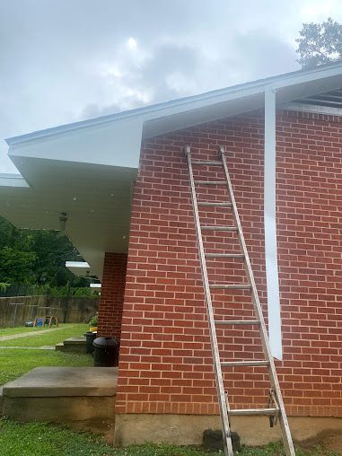 A ladder is leaning against the side of a brick house.