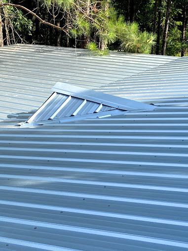 A close up of a metal roof with trees in the background.