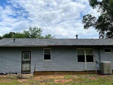 The back of a house with a roof and a few windows.