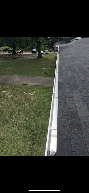 A roof with a gutter on the side of it next to a grassy field.