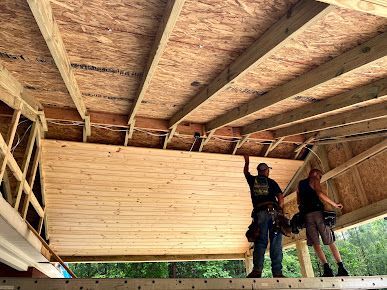 Two men are standing on top of a wooden structure.