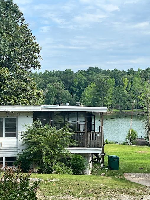 A mobile home is sitting on stilts next to a lake.