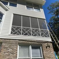 A house with a screened in porch and a ladder on the side of it.
