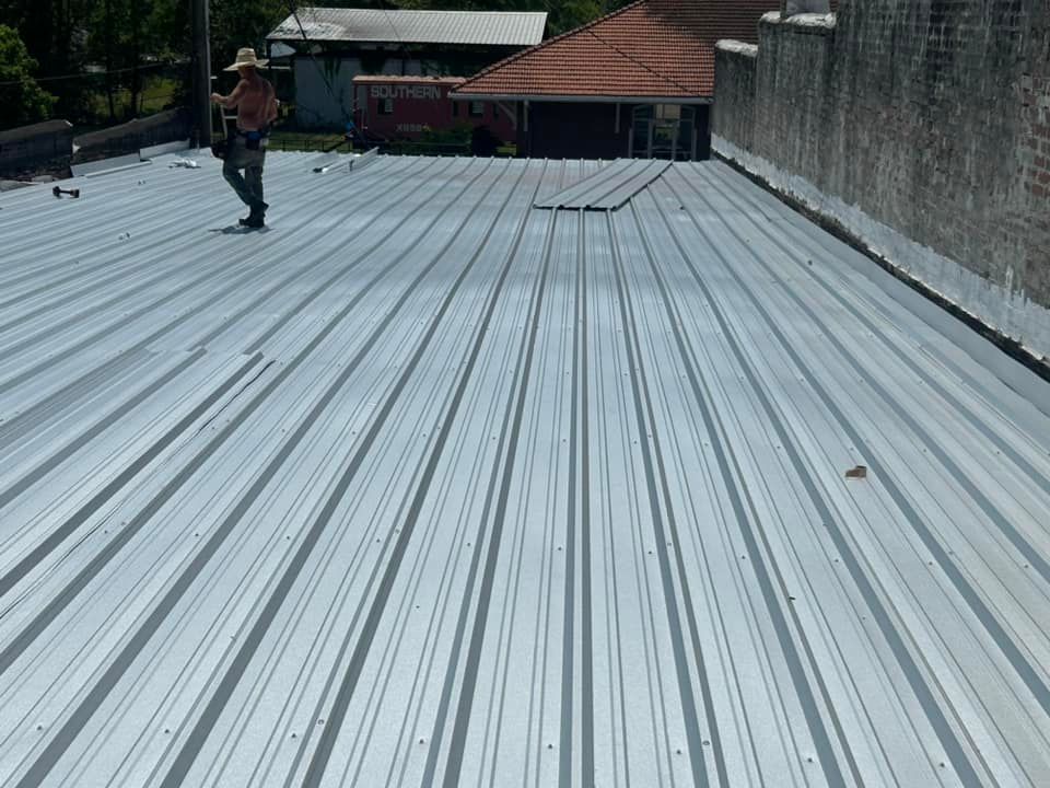 A man is standing on top of a metal roof.