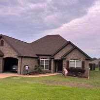 A couple of people are standing in front of a large brick house.