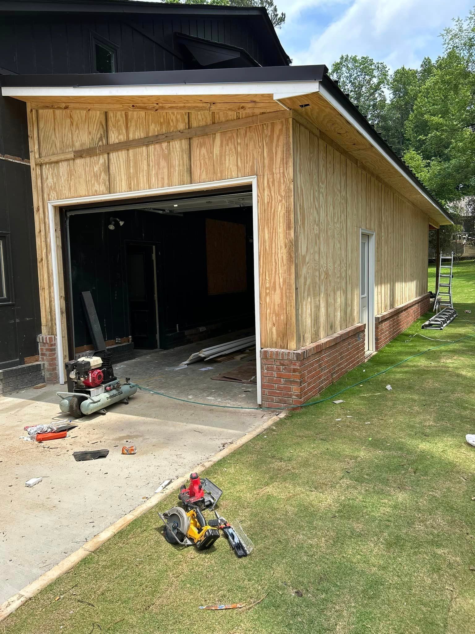 A garage is being remodeled and a tool bag is laying on the ground in front of it.