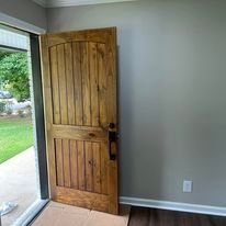 A wooden door is sitting in a room next to a window.