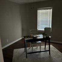 An empty room with a desk and chairs in front of a window.